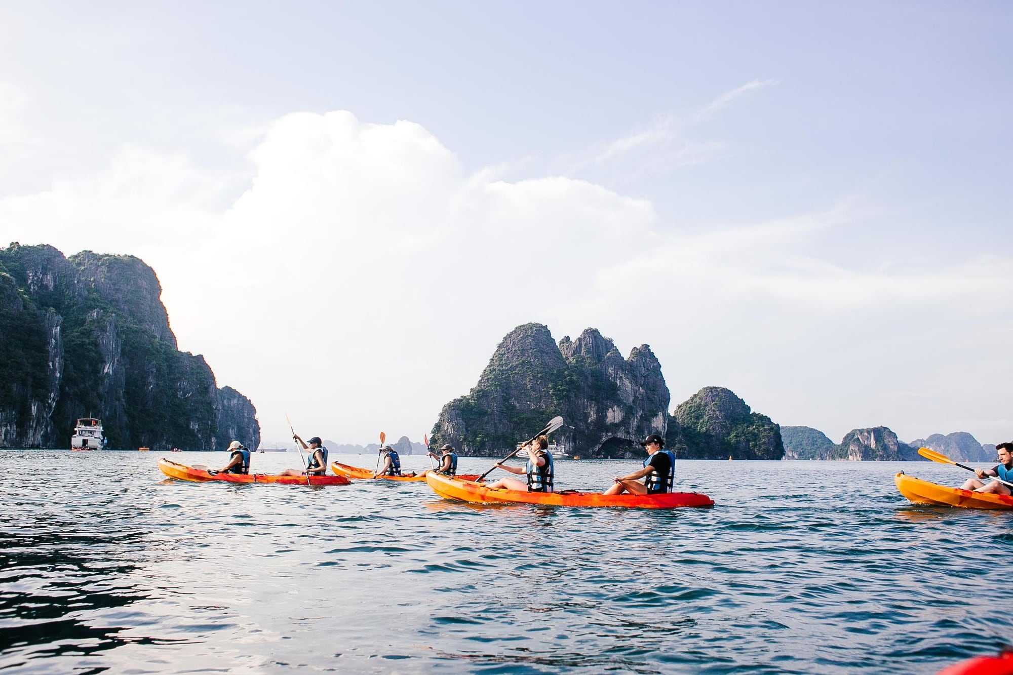 Kayakers paddling between limestone islands on a calm sea