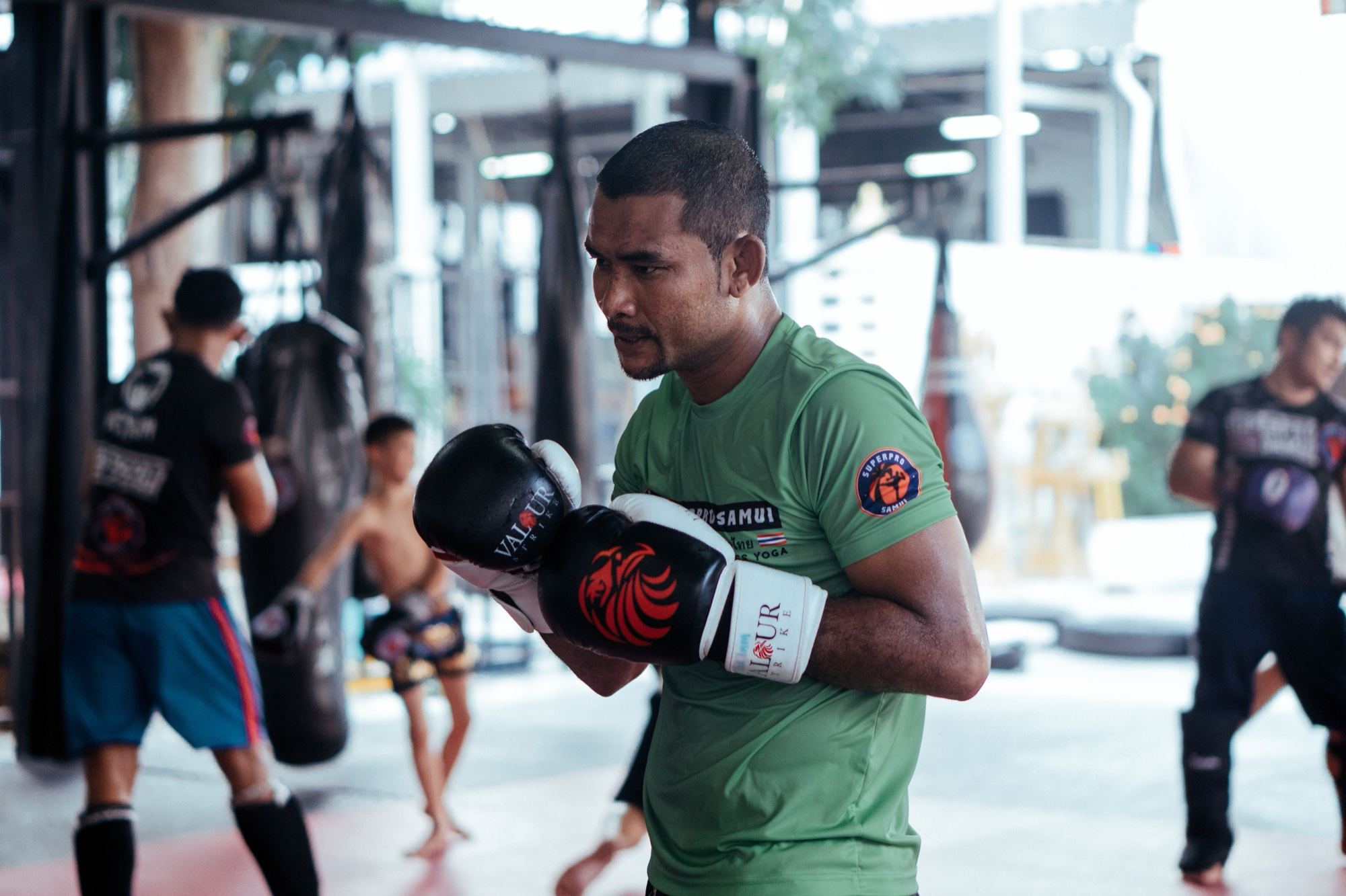 A Thai coach in gloves facing his student during a class in a Muay Thai gym in Chiang Mai, Thailand